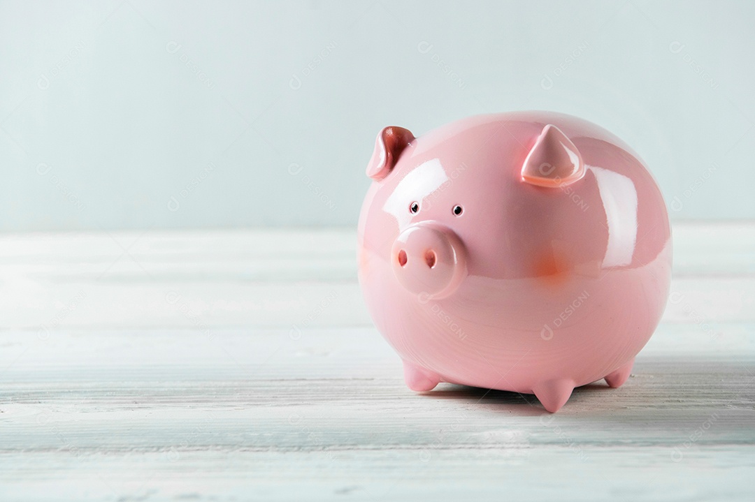 Cofrinho rosa no piso de madeira branca. Conceito de economia financeira e de dinheiro.