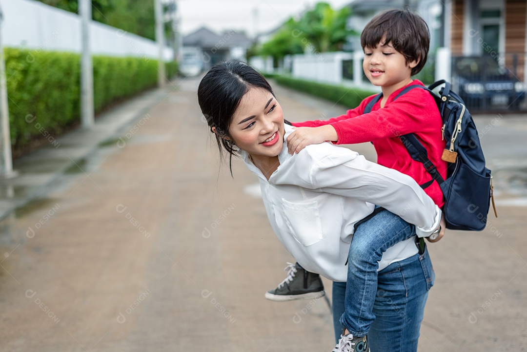 Single mother carrying and playing with her children near home with villa street background.