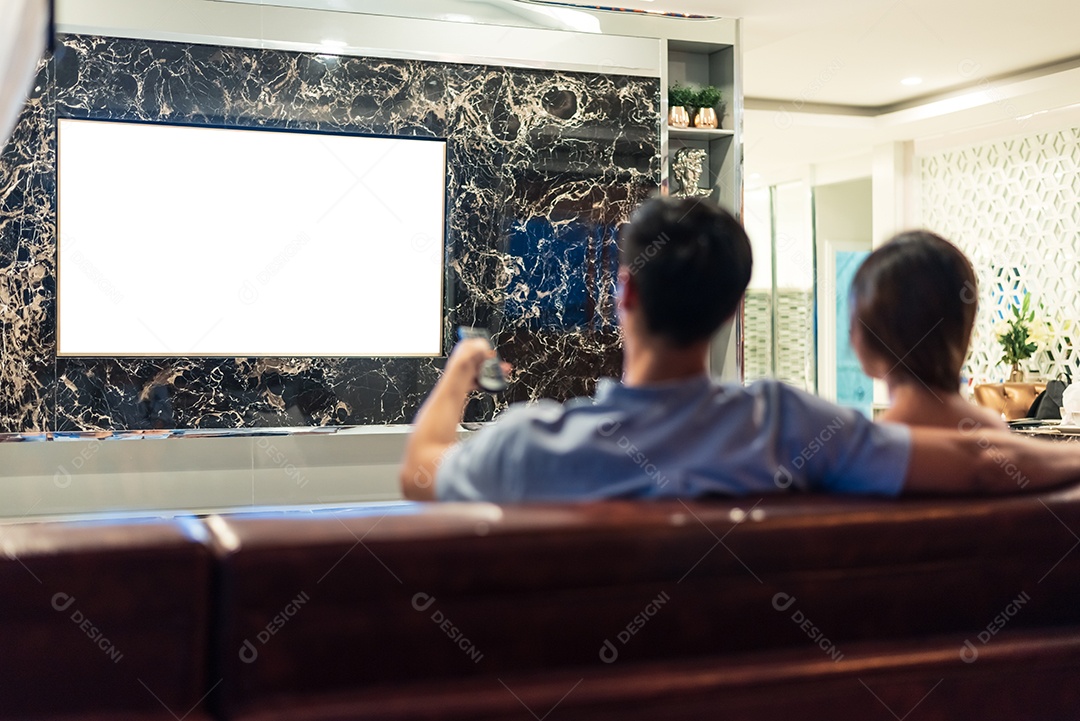 Casais asiáticos assistindo televisão de exibição de tela branca em branco para fundo de modelo de publicidade.