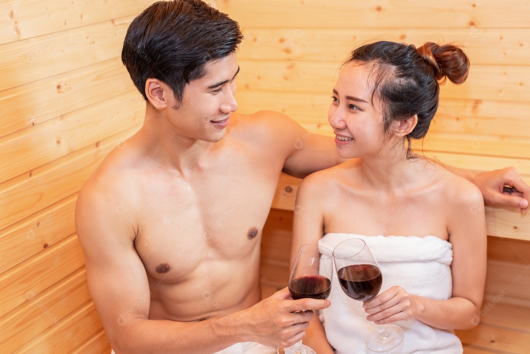 Casais asiáticos brindando e bebendo vinho na sala de sauna para comemorar o aniversário de casamento.