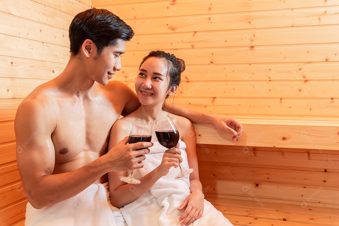 Casais asiáticos brindando e bebendo vinho na sala de sauna para comemorar o aniversário de casamento.