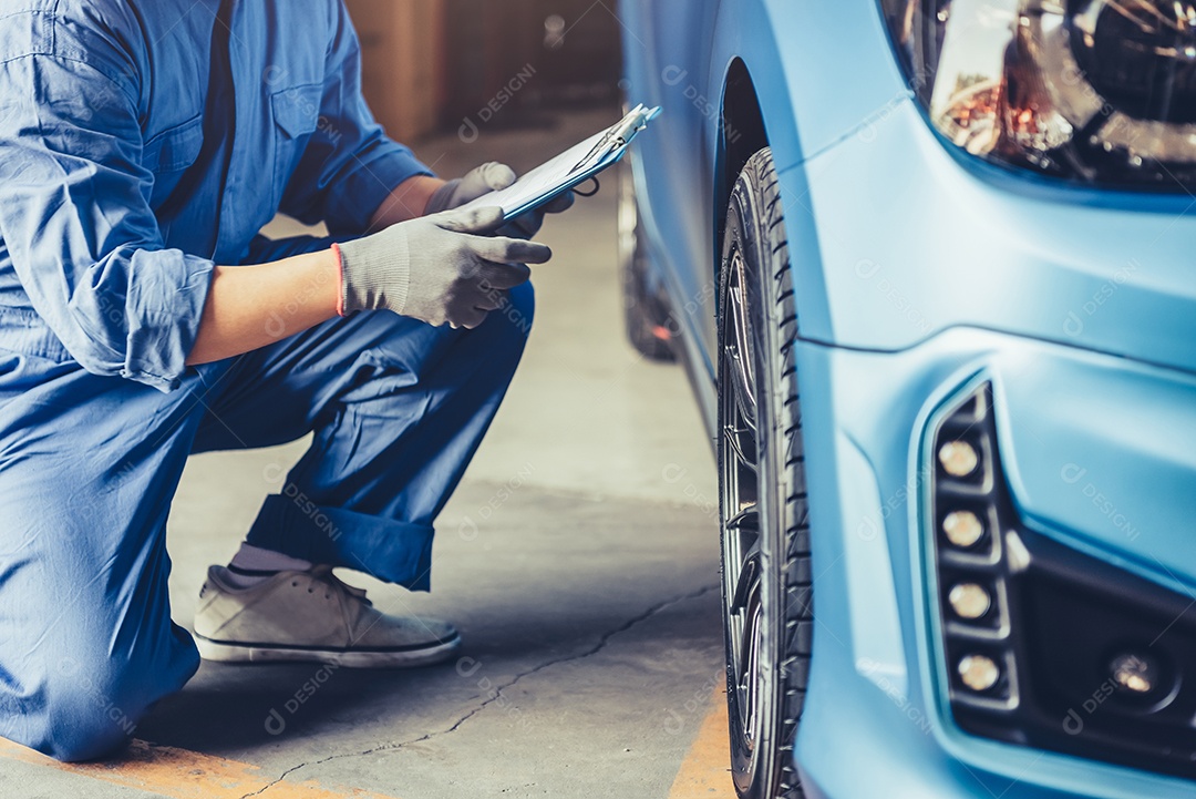 Técnico mecânico de automóveis asiáticos segurando a prancheta e verificando o veículo de manutenção pelo pedido de reclamação do cliente na garagem da oficina mecânica.