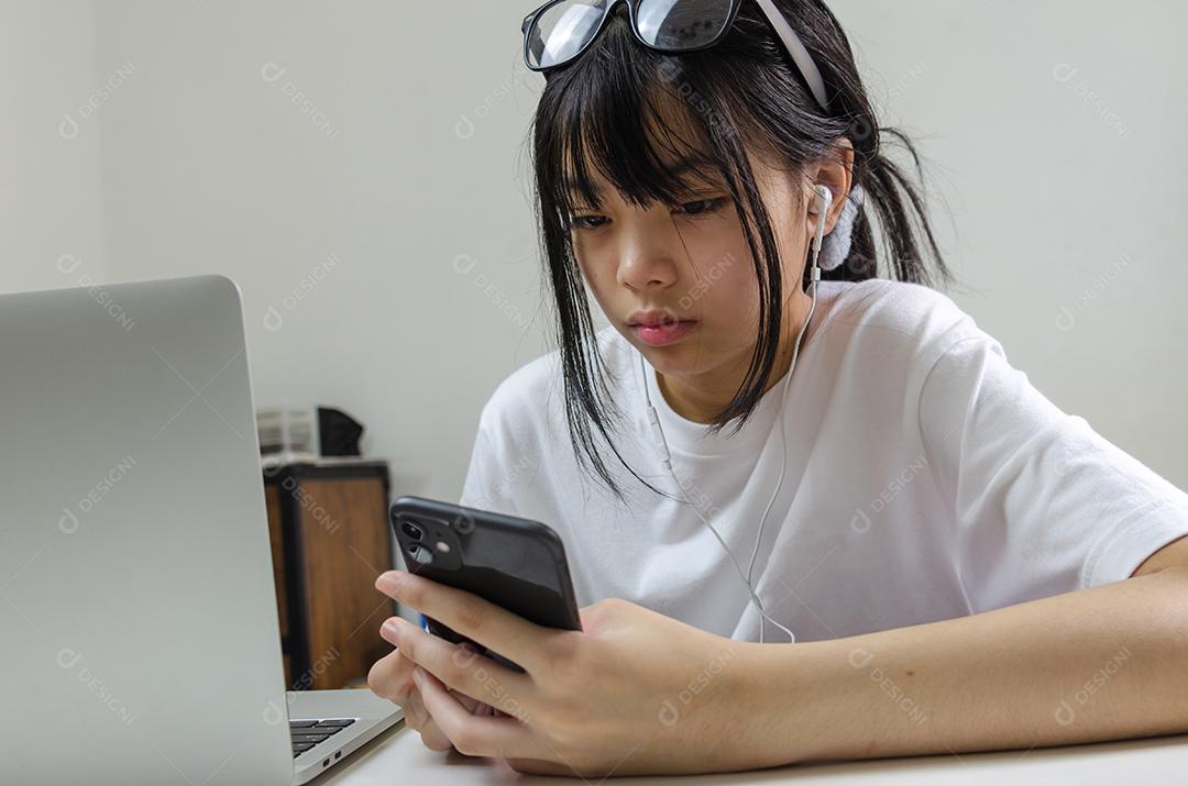 Menina segurando caneta escrevendo livro estudo aprendendo digital internet vídeo computador on-line laptop em casa.