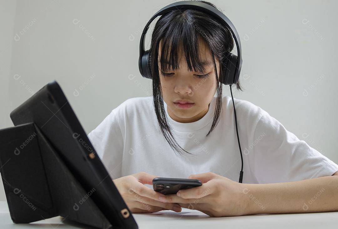 Garota usando fones de ouvido estudando on-line com o laptop do computador e ouvindo música relaxante ou reproduzindo mídias sociais da internet em casa.