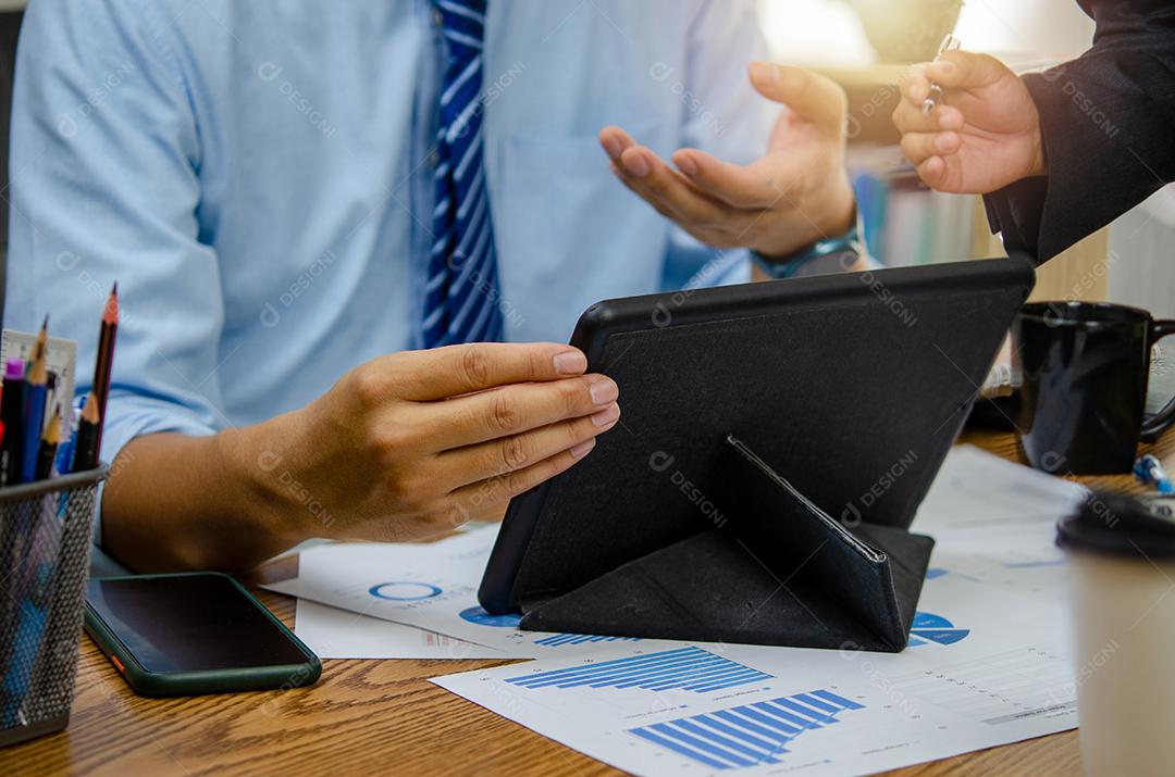 Empresários reunidos no escritório analisando dados de gráficos financeiros e gráficos de investimento para planejar uma equipe de marketing.