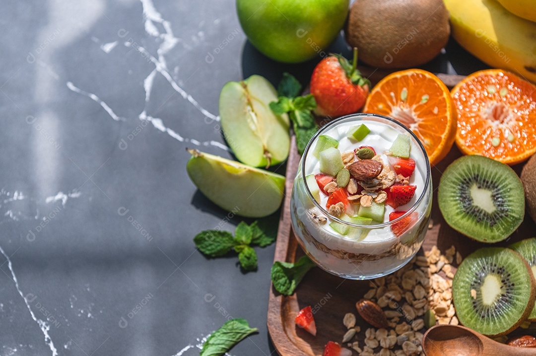 Iogurte de nutrição closeup com muitas frutas na mesa e mão do chef. Cozinha alimentar e conceito de bebidas. Tema de sobremesa orgânica.