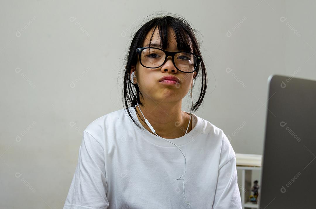Garota usando fones de ouvido estudando on-line com o laptop do computador e ouvindo música relaxante ou reproduzindo mídias sociais da internet em casa.