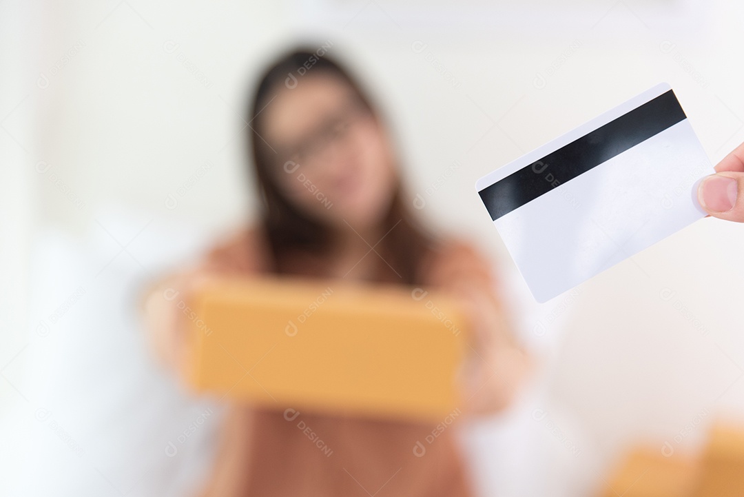 Close-up de cartão de crédito com mulher empresária e fundo de caixa de encomendas.
