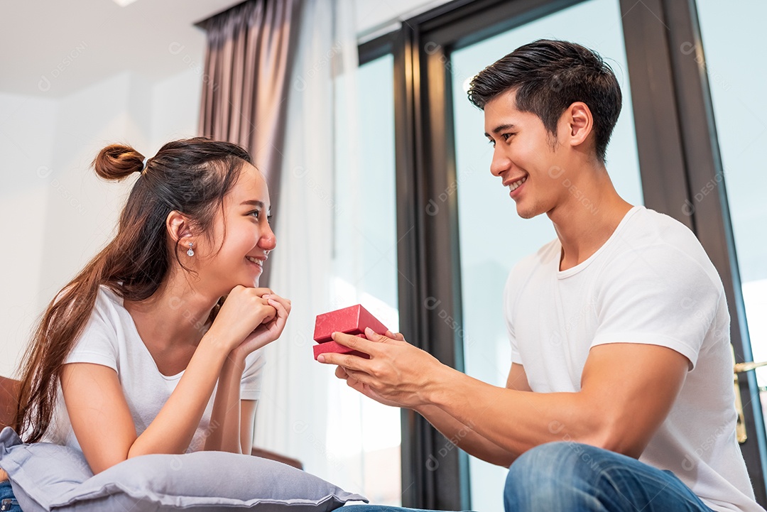 Homem segurando caixa de presente para namorada surpresa em sua casa. Mulher esperando o namorado do formulário de presente do dia dos namorados.