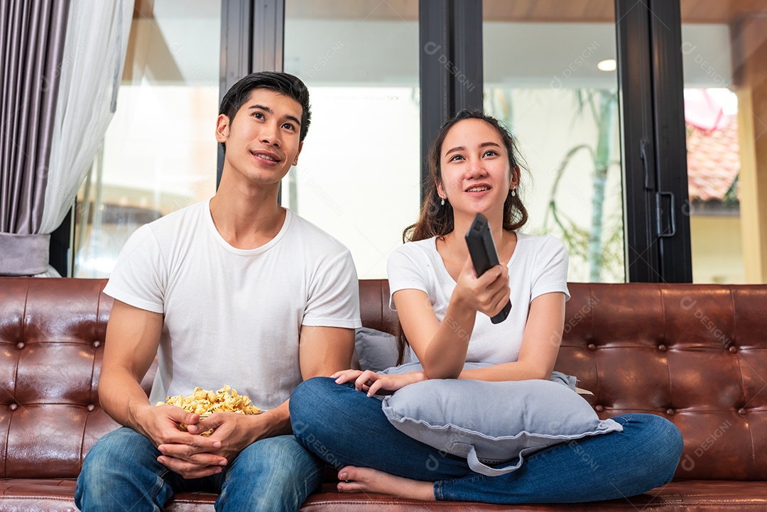 Casais asiáticos assistindo televisão juntos no sofá em sua casa. Conceito de pessoas e estilos de vida. Conceito de férias e férias. Tema lua de mel e pré casamento. Atividade familiar feliz no dia dos namorados.