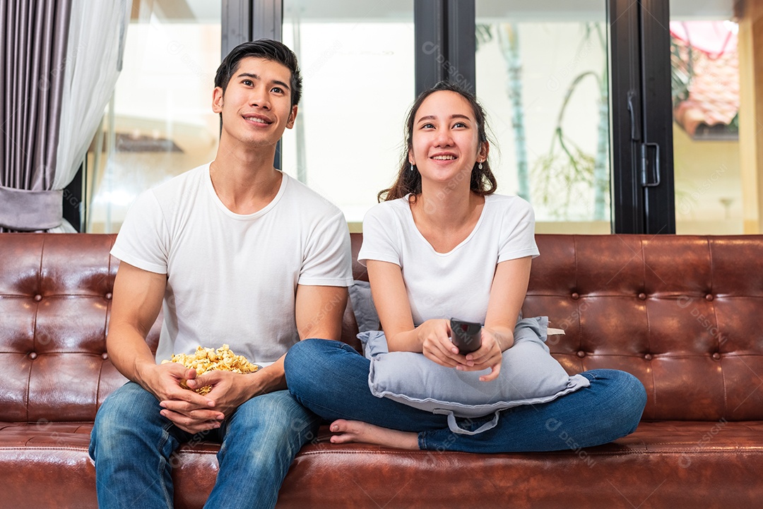 Casais asiáticos assistindo televisão juntos no sofá em sua casa. Conceito de pessoas e estilos de vida. Conceito de férias e férias. Tema lua de mel e pré casamento. Atividade familiar feliz no dia dos namorados.
