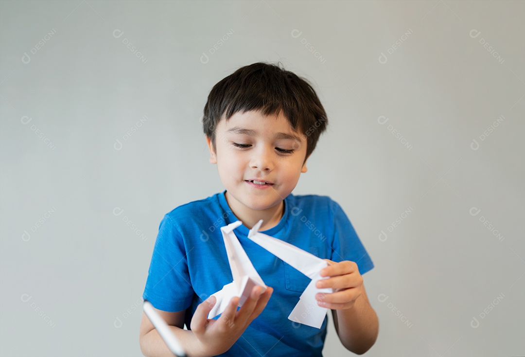 Menino de escola feliz olhando papel origami Swan em suas mãos.