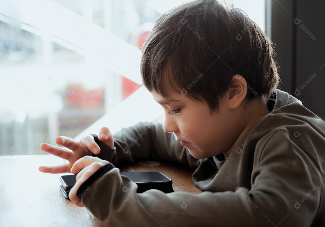 Garoto de retrato chave alto jogando jogo no celular enquanto espera por comida