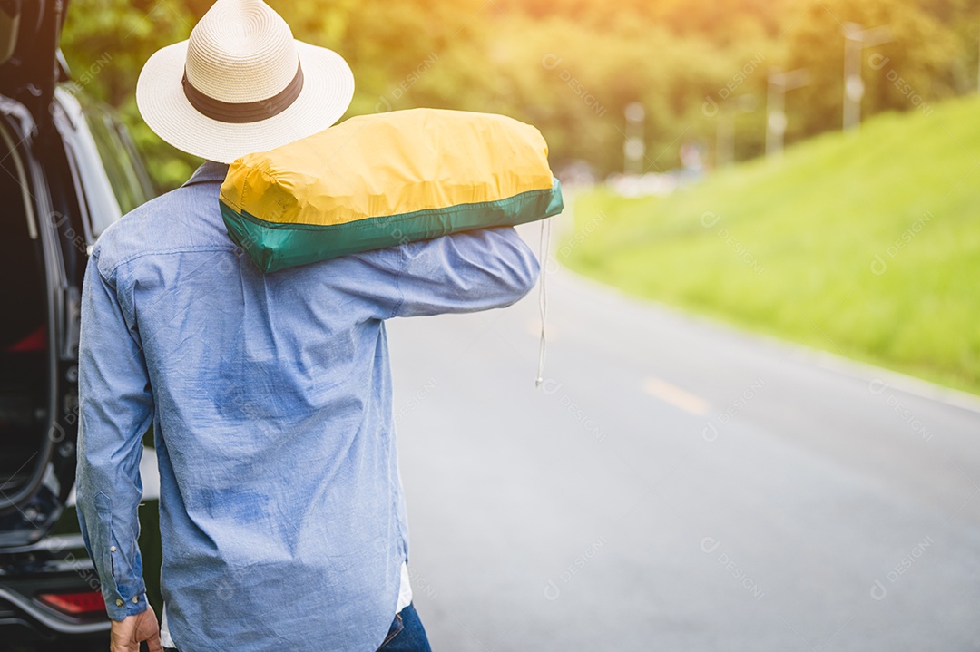 Vista traseira do turista caminhando pela estrada com bolsa durante a viagem no campo. Estilos de vida de pessoas e conceito de férias. Homem segurando e mochila para longa viagem de férias com fundo de montanha.