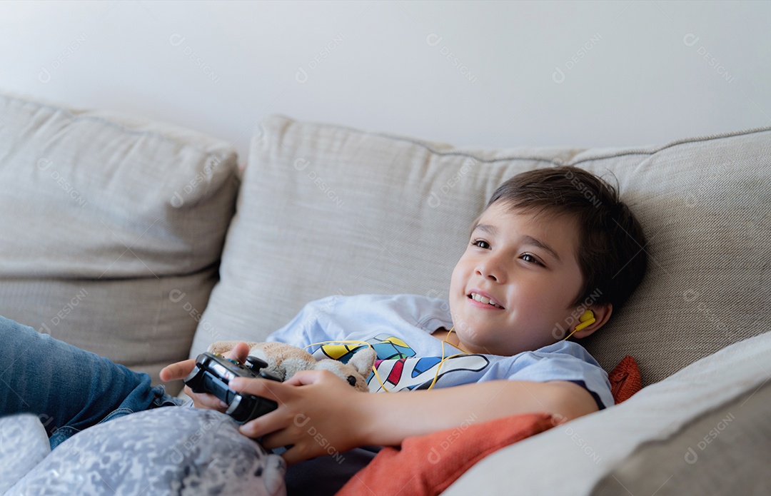 garoto sentado no sofá com o brinquedo do cachorro assistindo TV