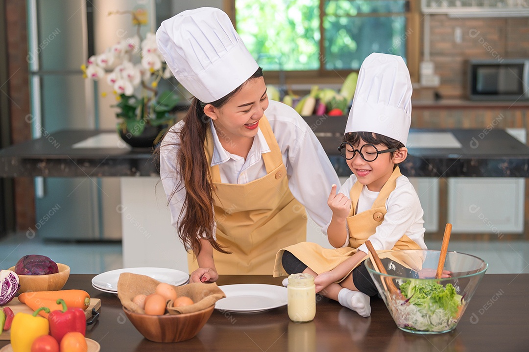 Feliz linda mulher asiática e menino bonitinho com óculos se preparam para cozinhar na cozinha em casa.