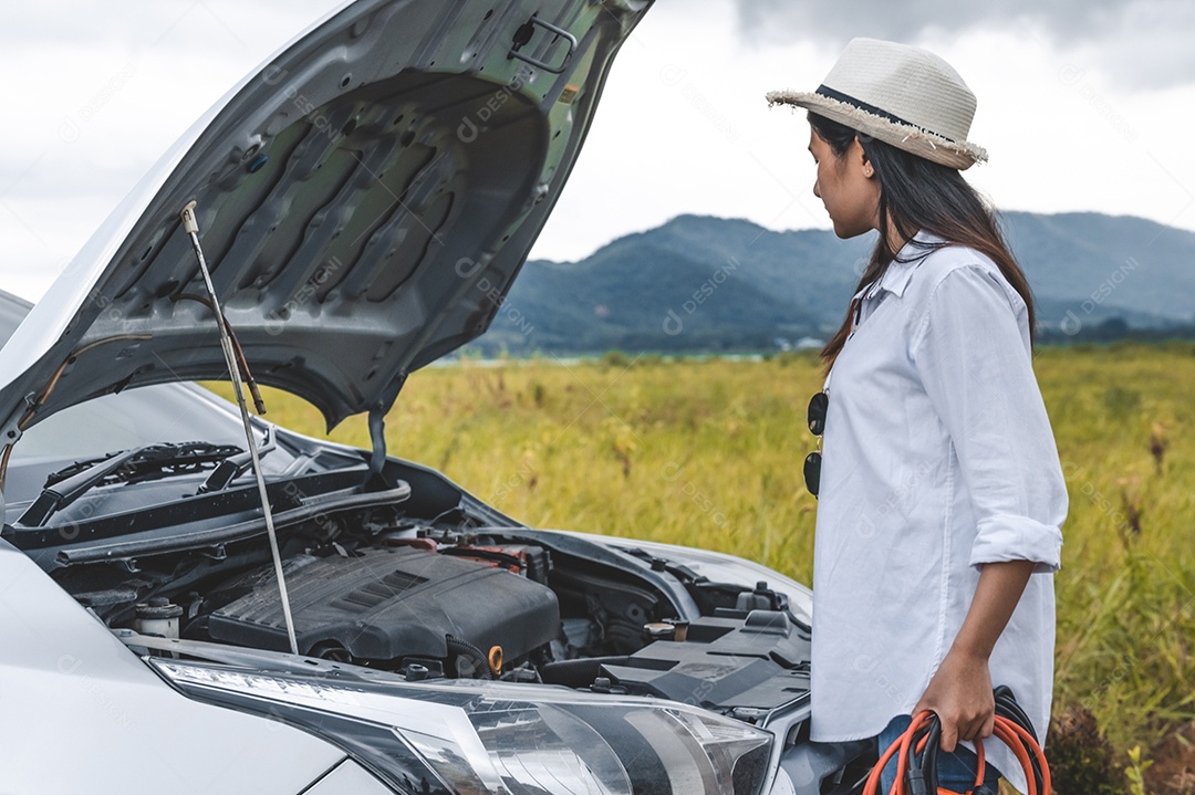 Mulher asiática segurando o fio de cobre do cabo de reforço da bateria para reparar o carro quebrado.