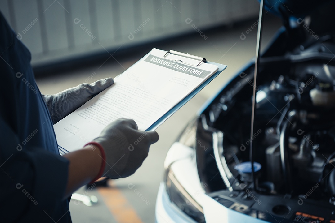 Mecânico de automóveis segurando a prancheta e verificando o veículo de manutenção pelo pedido de reivindicação de seguro do cliente na garagem da oficina mecânica.