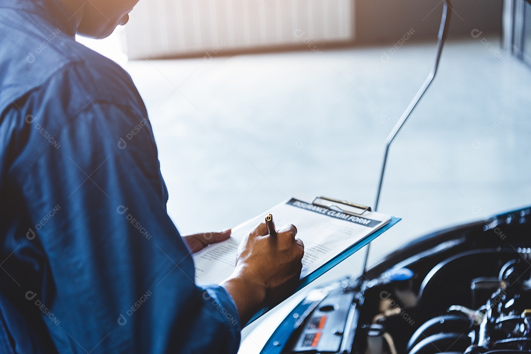 Mecânico de automóveis segurando a prancheta e verificando o veículo de manutenção pelo pedido de reclamação do cliente na garagem da oficina mecânica.