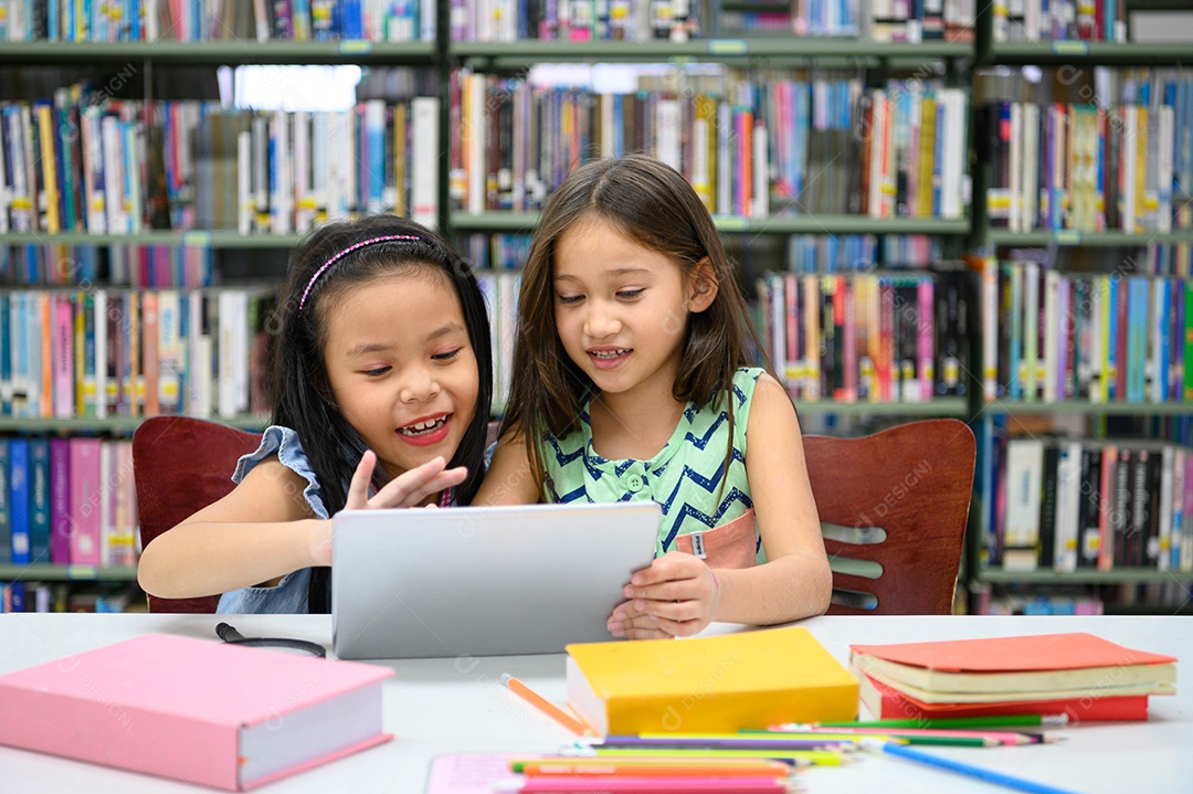 Duas garotinhas felizes brincando em um desenvolvedor de computação tablet PC.