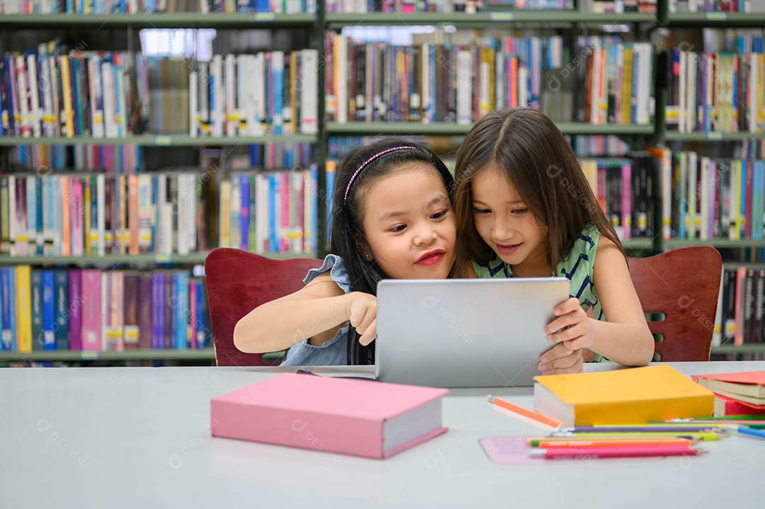 Duas garotinhas felizes brincando em um desenvolvedor de computação tablet PC.