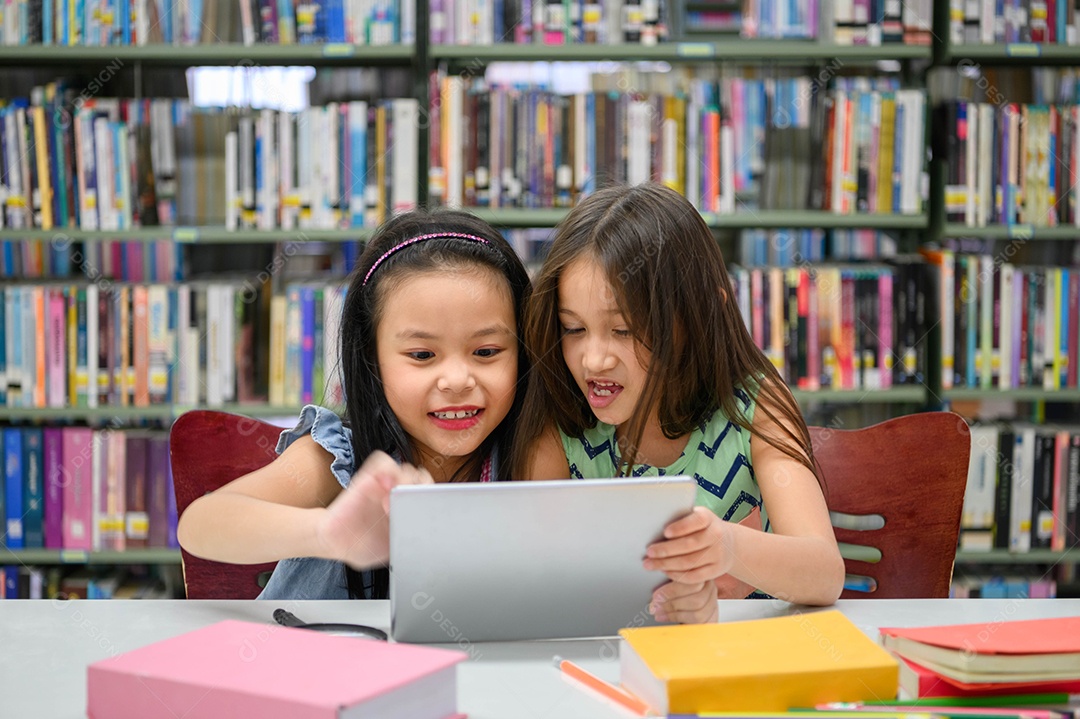 Duas garotinhas felizes brincando em um desenvolvedor de computação tablet PC.