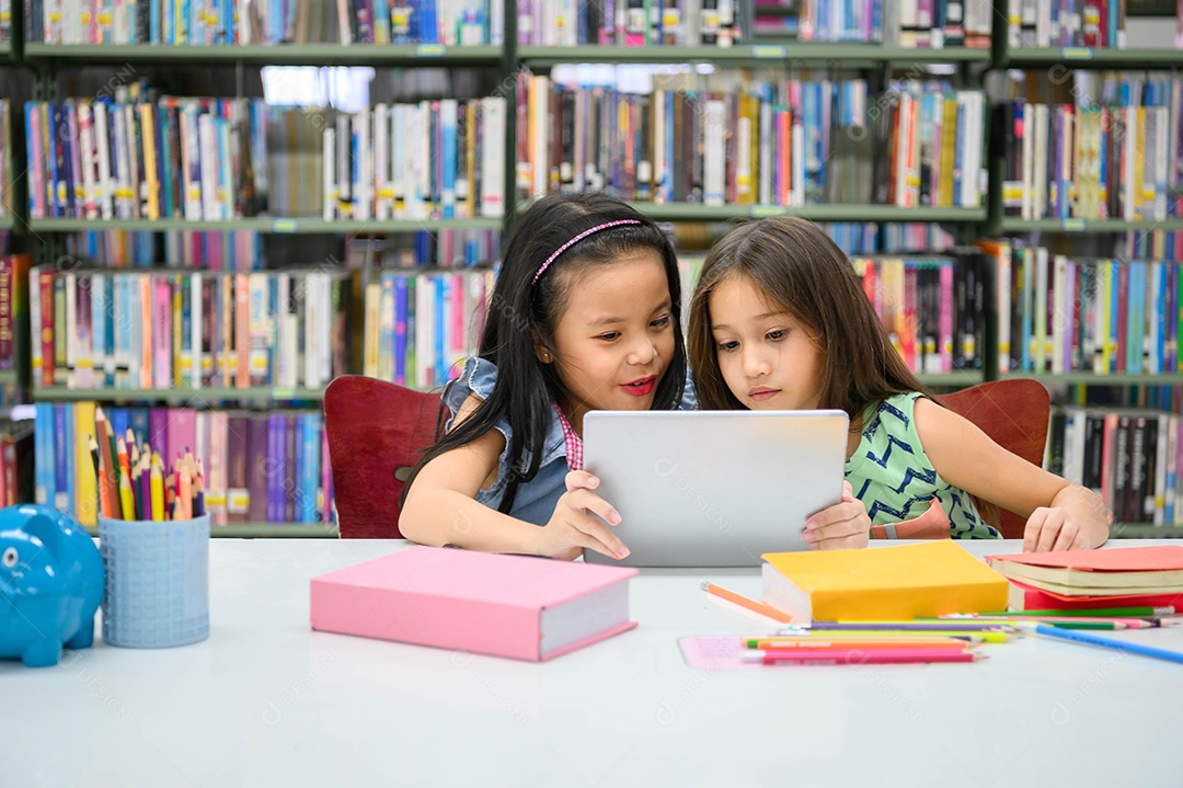 Duas garotinhas felizes brincando em um desenvolvedor de computação tablet PC.