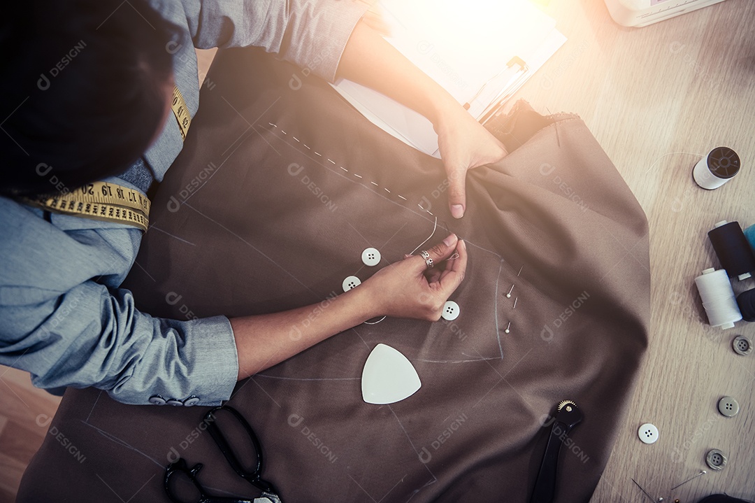 Vista superior da linda costureira costurando tecido de vestido com a mão.