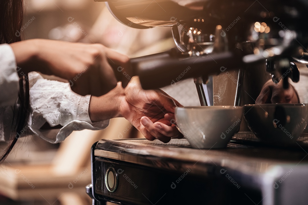 Detalhe da mão profissional de barista feminina fazendo café.