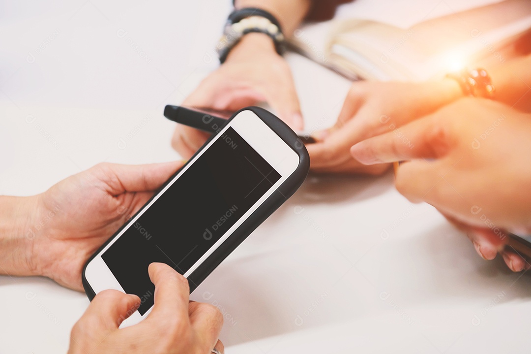 Mão de amigos multirraciais usando telefone móvel viciado.