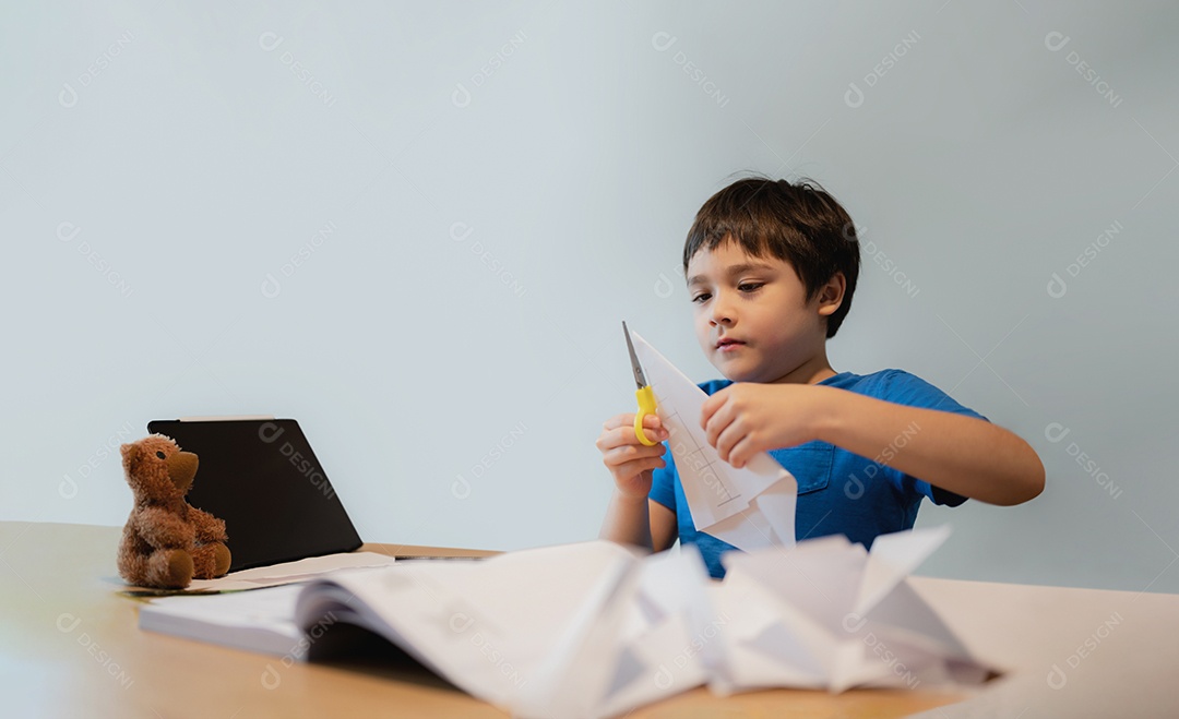 Garoto usando tesoura cortando papel branco, Estudante fazendo cisne de origami para seu dever de casa