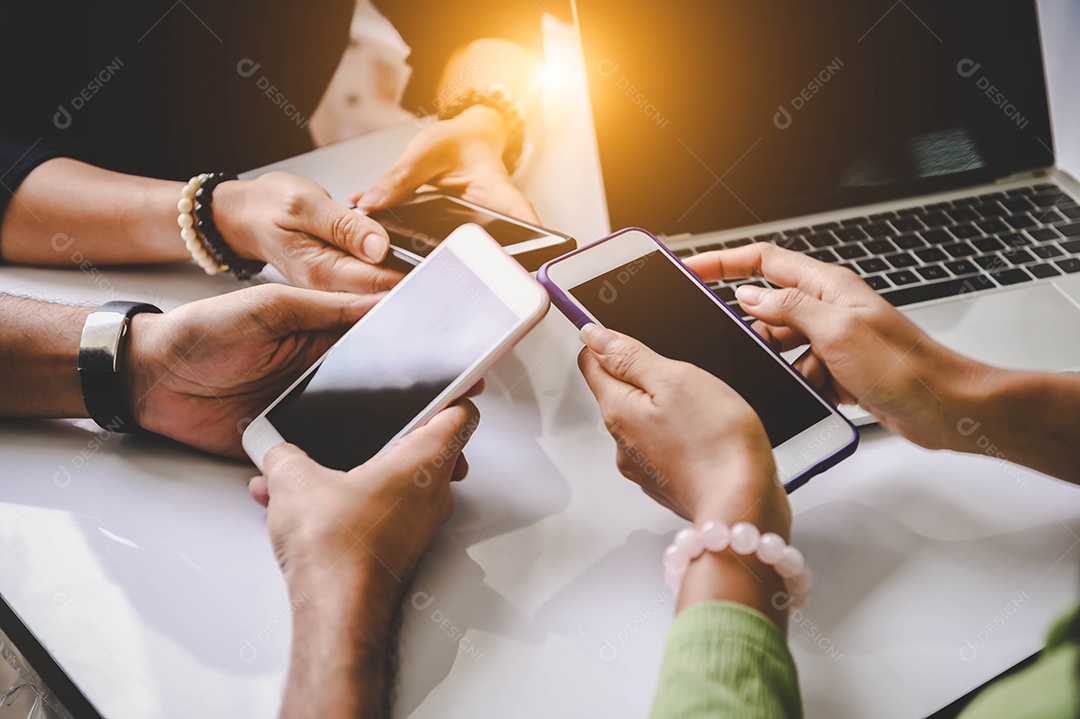 Grupo de jovens descolados segurando o telefone nas mãos no escritório.