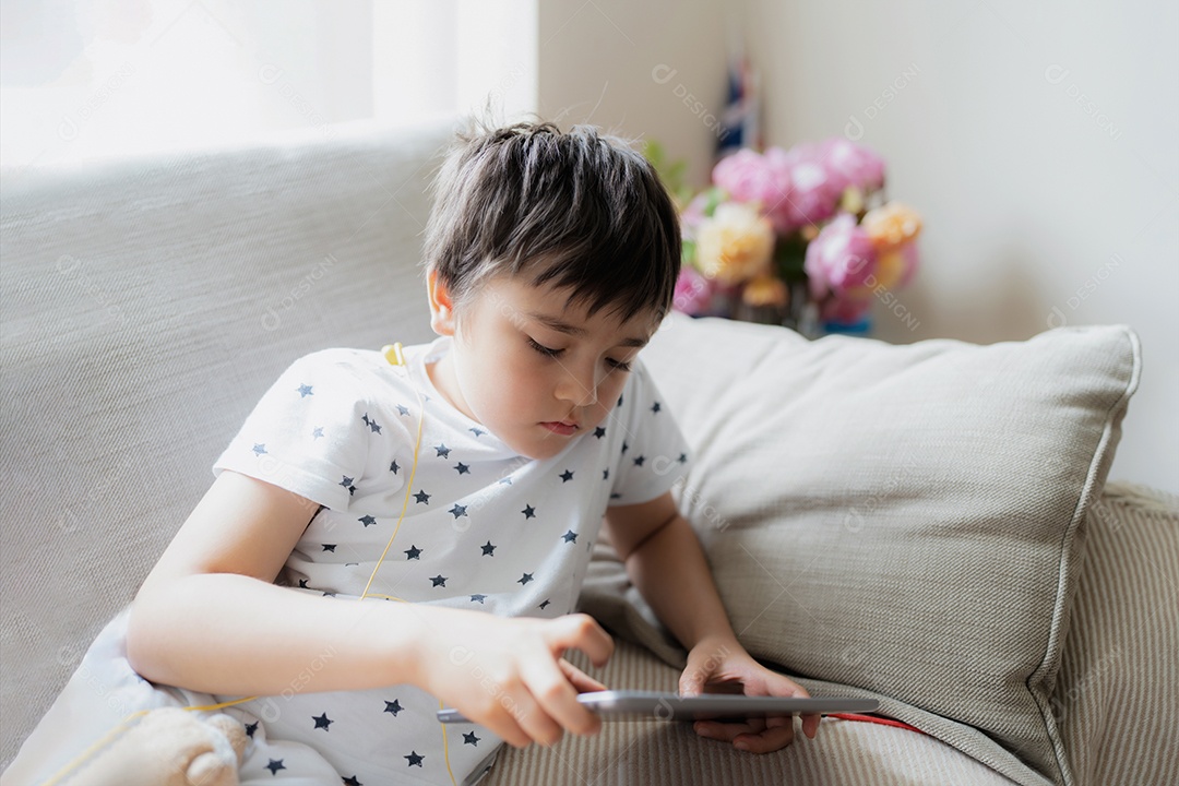 Garoto de retrato chave alto jogando jogo no tablet sentado no sofá