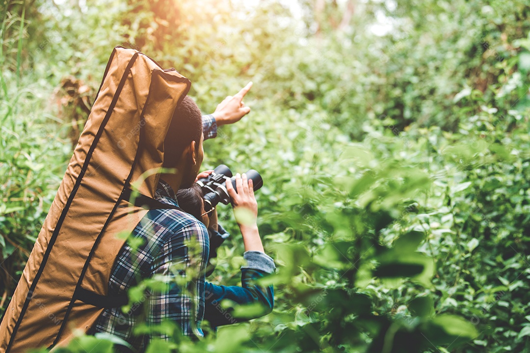 Casal de asiáticos segurando binóculos telescópio na floresta.