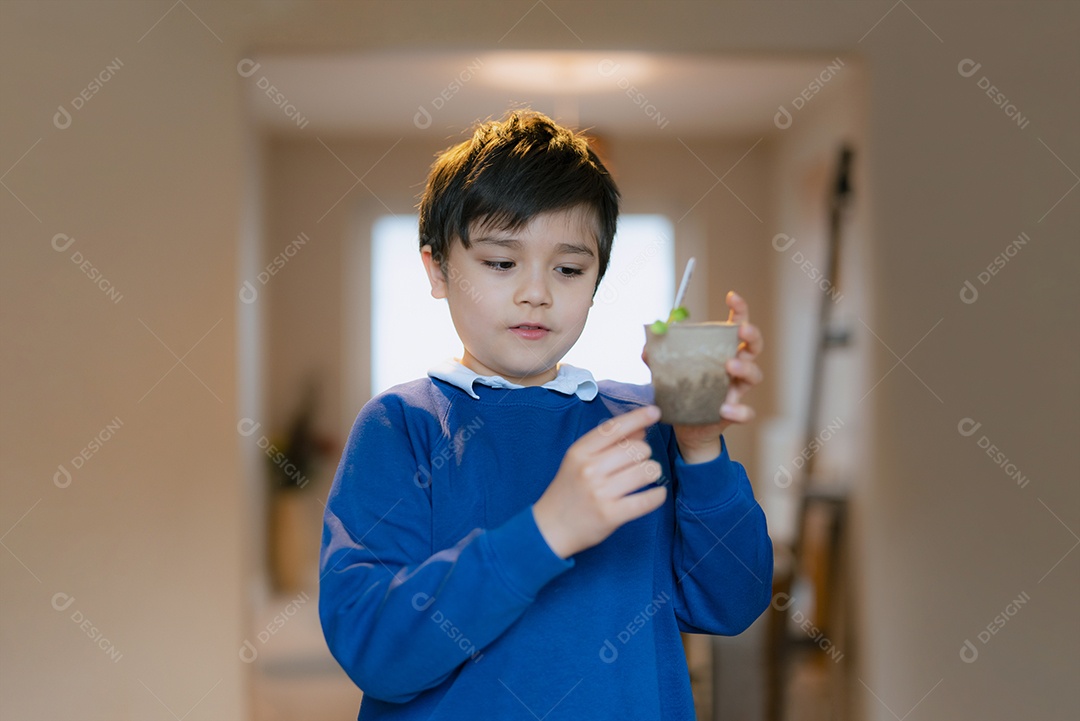 Garoto da escola segurando um broto verde no pote,