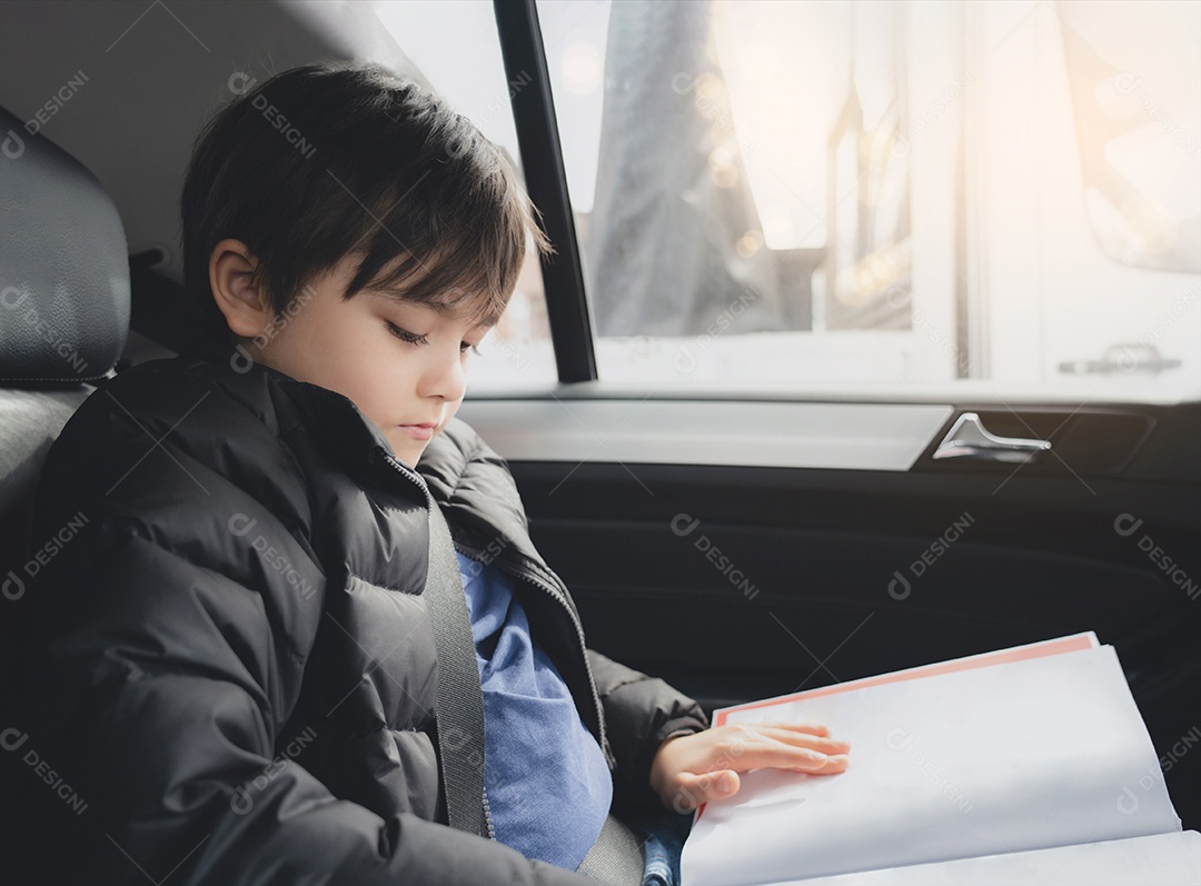 Criança sentada no banco do carro e lendo um livro