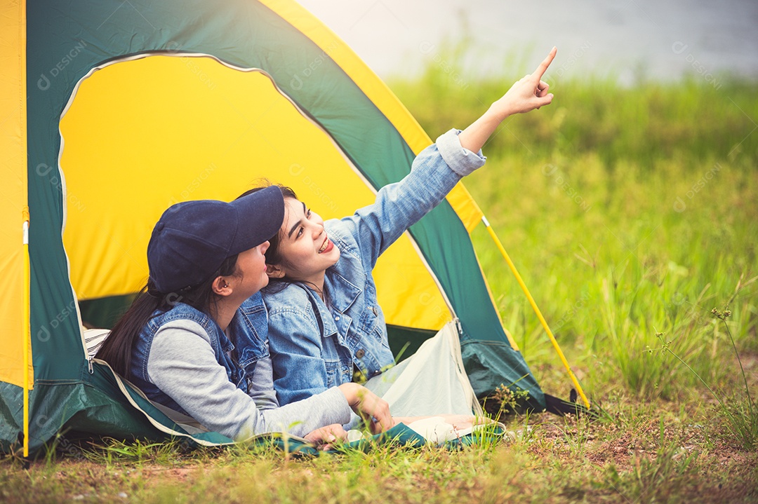 Asian friendship of two close friends relax in camping tent in green.