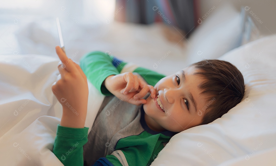 Criança deitada na cama usando tablet lendo história antes de dormir