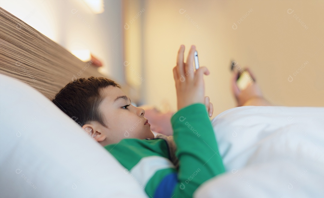 Garoto feliz deitado na cama segurando o tablet assistindo desenho animado e conversando com amigos no teclado digital