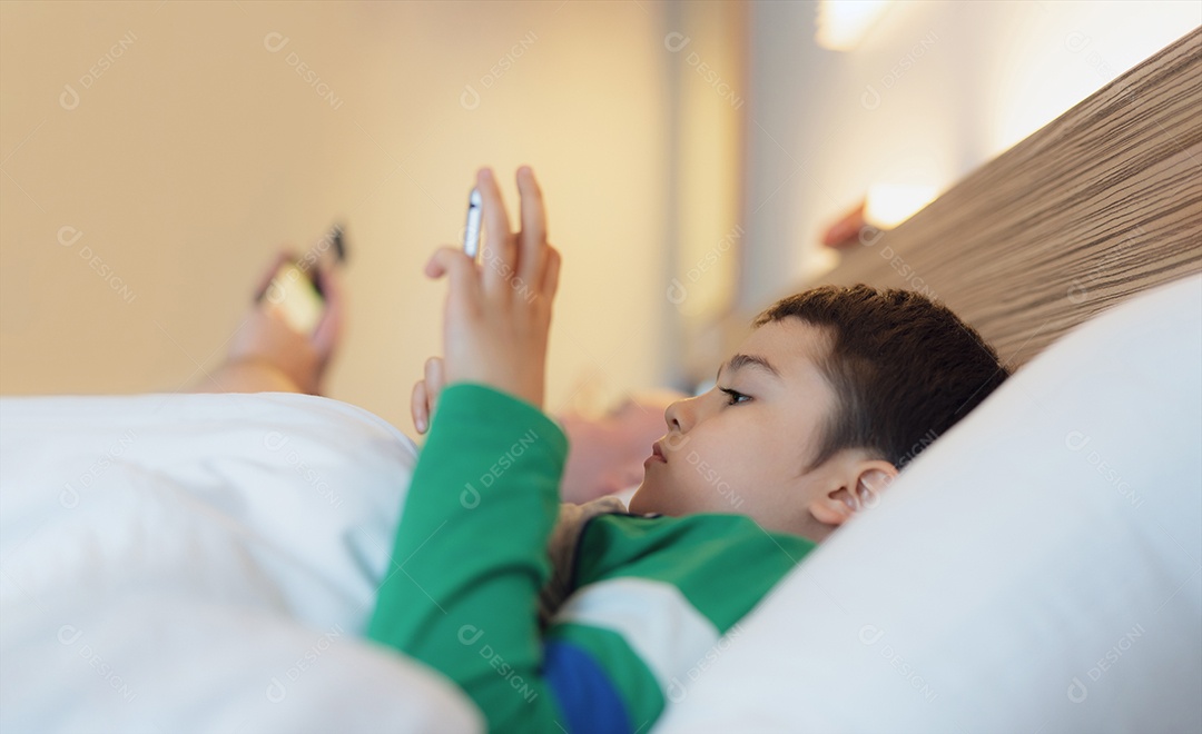 Garoto feliz deitado na cama segurando o tablet assistindo desenho animado e conversando com amigos no teclado digital