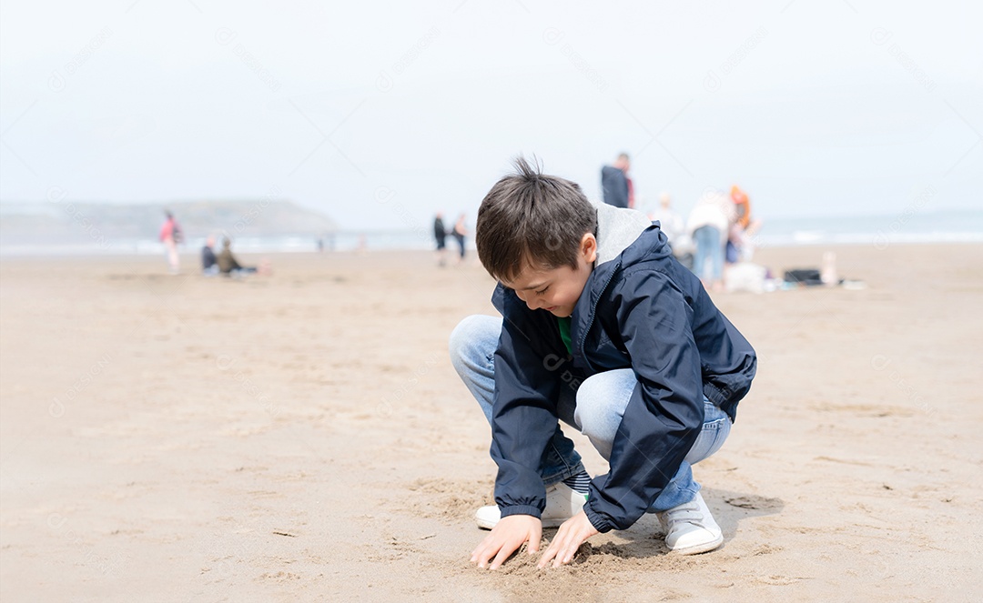 Retrato menino feliz jogando e cavando areia na praia em um dia ensolarado de verão