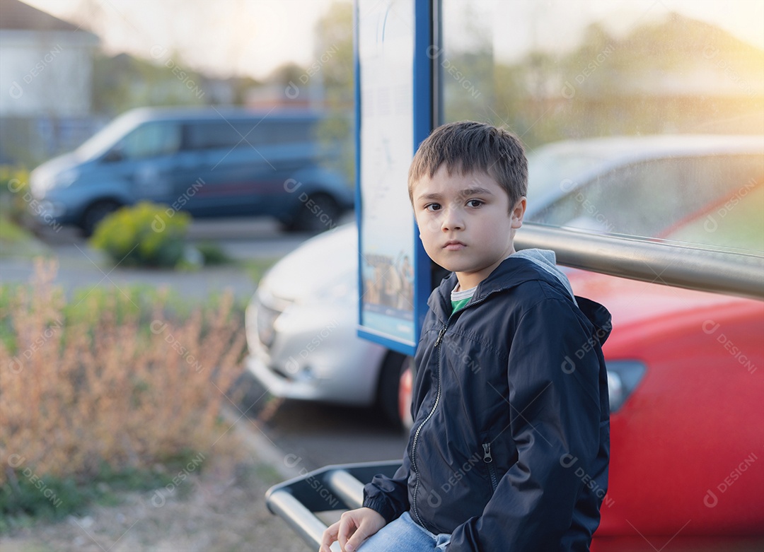 Garoto sentado no ponto de ônibus esperando o ônibus