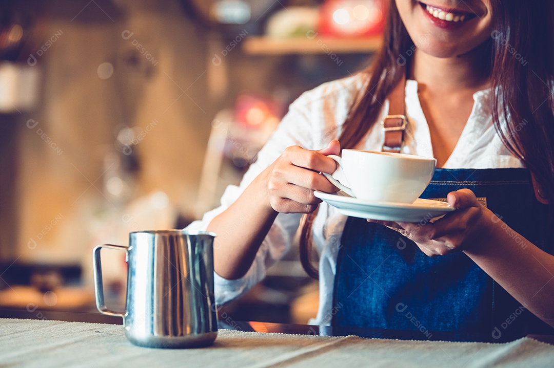 Close-up da mão de barista feminina profissional fazendo e segurando a xícara de café branca.