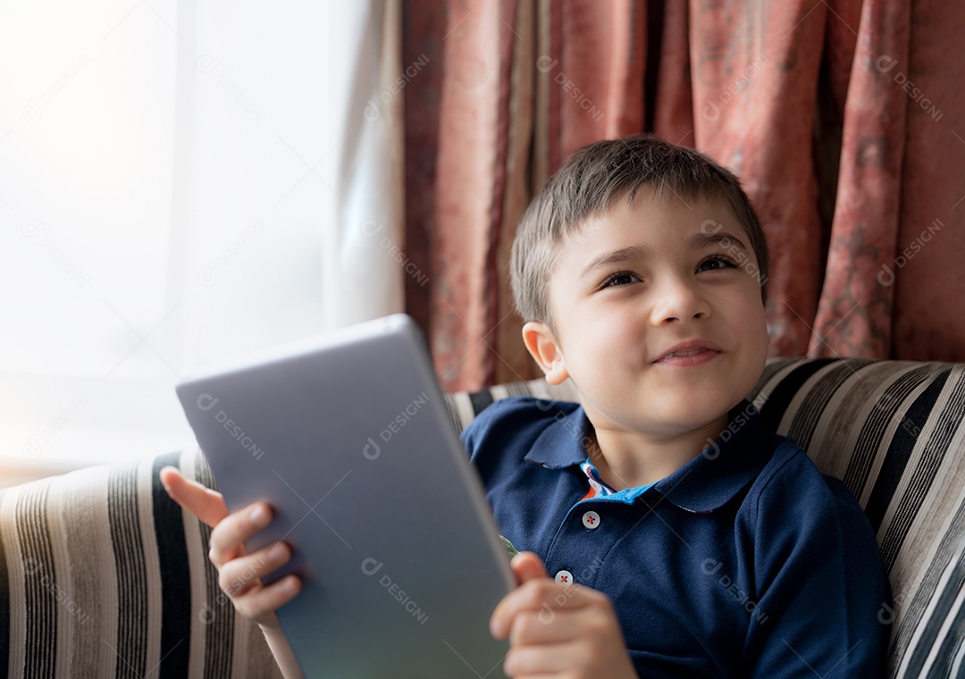 Menino feliz usando o jogo de tablet online no tablet da internet