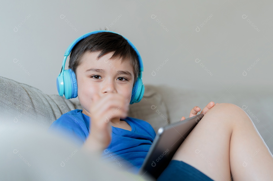 Menino feliz usando fones de ouvido ouvindo música.