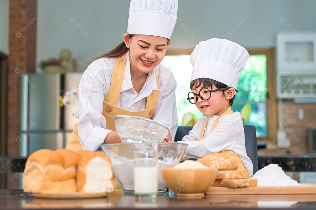 Menino asiático bonitinho e linda mãe peneirando farinha de massa.