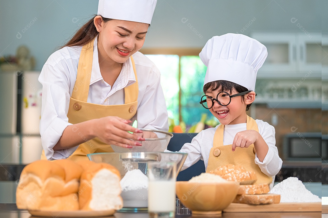 Menino asiático bonitinho e linda mãe peneirando farinha de massa.