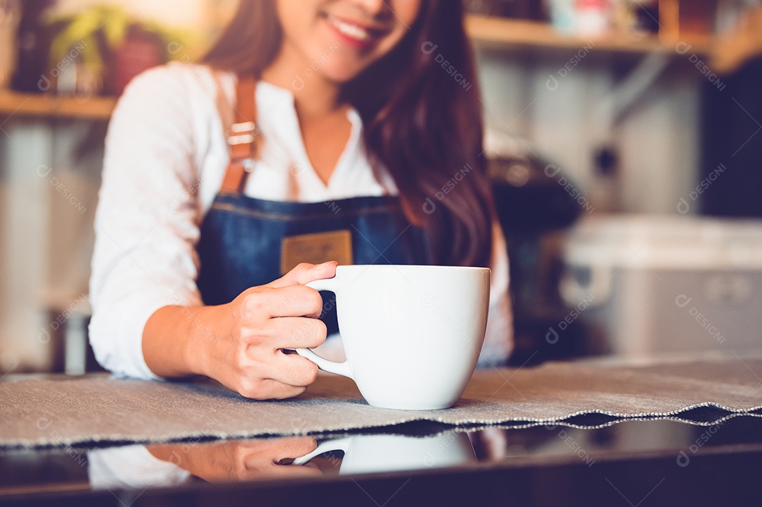 Aproximação da xícara de café branca com uma linda mulher asiática barista.