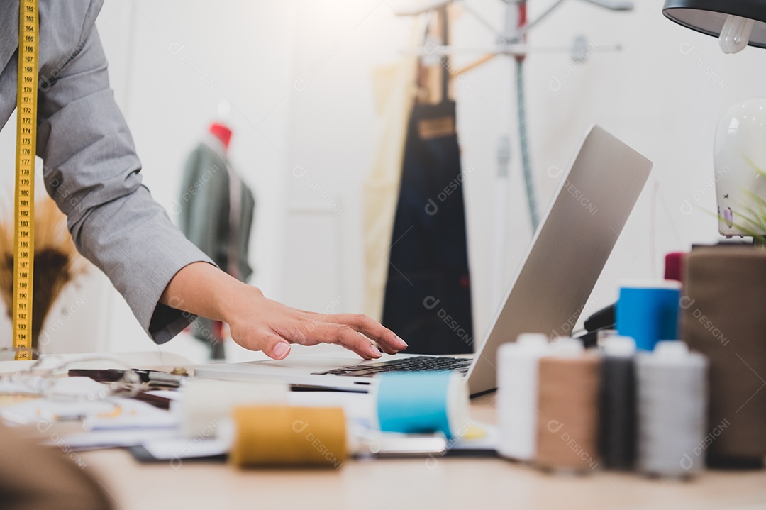 Close-up da mão de designer de moda feminina trabalhando em loja de roupas.