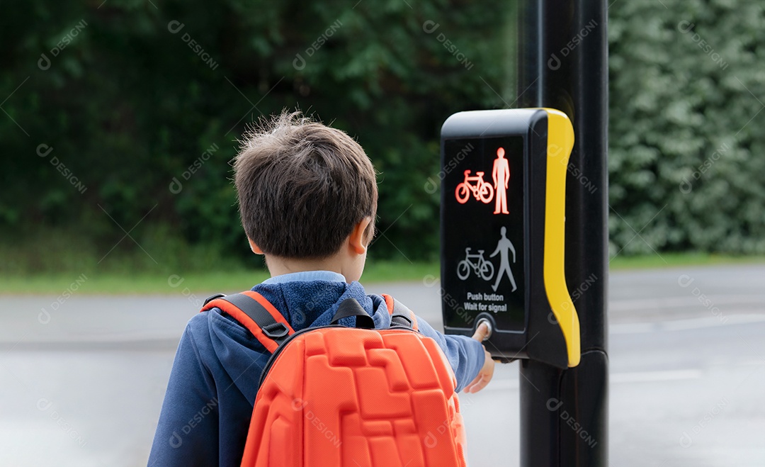 Retrato da vista traseira Criança da escola pressionando o botão nos semáforos na passagem para pedestres a caminho da escola.